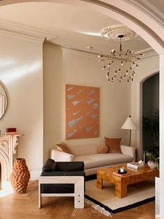 a living room filled with furniture and a fire place under a chandelier in front of a mirror