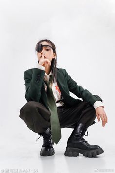 a woman in a suit and tie squatting down with her hand on her mouth