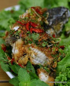 a white plate topped with fish covered in herbs and sauce on top of lettuce