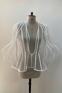 a mannequin with white sheer fabric on it's shoulders and neckline