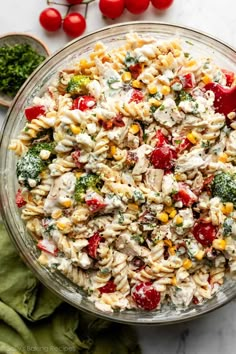 a bowl filled with pasta salad next to tomatoes and broccoli