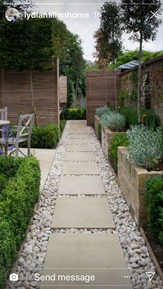 an outdoor garden with stone walkways and plants on either side, along with wooden fences