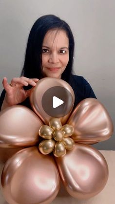 a woman sitting at a table in front of a large balloon flower