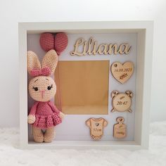 a crocheted frame with a stuffed animal and personalized items in the shape of a bunny