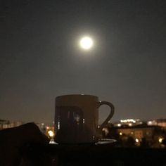 a coffee cup sitting on top of a wooden table next to a cityscape