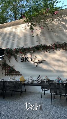 an outdoor seating area in front of a building with flowers growing on the side of it