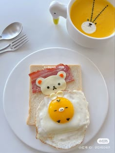 an egg, ham and cheese sandwich on a white plate with a cup of soup