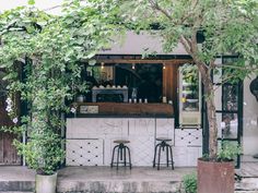 two stools are sitting in front of a small bar with plants growing on it