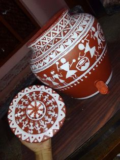 a red and white vase sitting on top of a wooden table