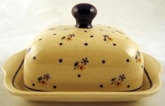 a yellow casserole dish with black handles and floral designs on the front, sitting on a white surface