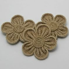 three crocheted flowers on a white surface