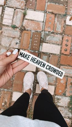 a person holding up a sticker that says make heaven crowded on the side of their feet