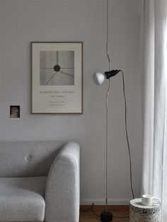 a living room with a white couch and a black lamp on the floor next to a window