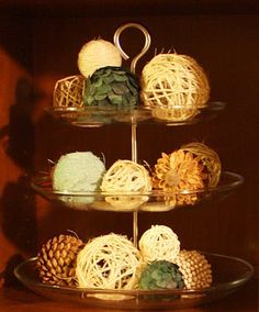 three tiered glass plate holding balls of yarn and pine cones