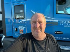 a man sitting in front of a blue truck with the words seaborn transport on it