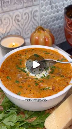 a white bowl filled with soup next to some vegetables and cheese on a cutting board