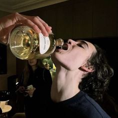 a man drinking from a bottle while another person looks on