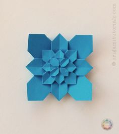 a blue origami flower on a white wall