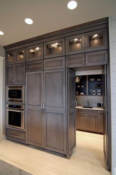 a kitchen with wooden cabinets and stainless steel appliances in the center, along with recessed lighting