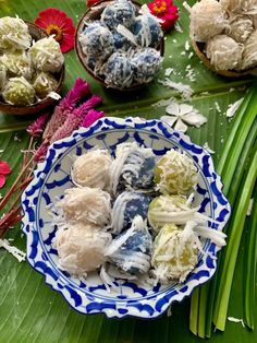 several different types of candies in bowls on a table with flowers and palm leaves