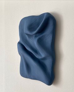 a blue sculpture hanging on the wall next to a white wall with a black object in it