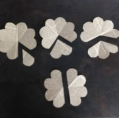 four pieces of paper cut out to look like shamrocks on a black table top