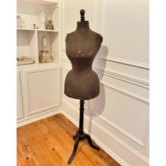 an old mannequin is sitting on a stand in front of a white wall