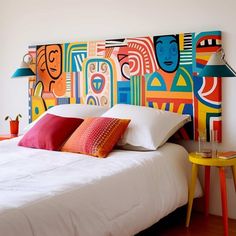 a bed with pillows and colorful headboard in a bedroom