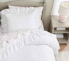 a white bed with ruffled sheets and pillows