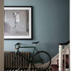 a bicycle parked next to a painting on the wall in a room with blue walls and black and white checkered flooring