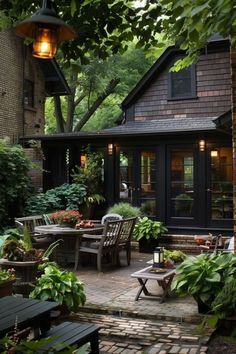 an outdoor patio with chairs and tables surrounded by greenery, shrubs and trees in front of a house