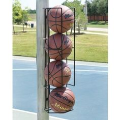 three basketballs are stacked on top of each other in a rack at the end of a basketball court