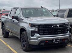 a silver truck parked in a parking lot next to other cars and trucks on a cloudy day