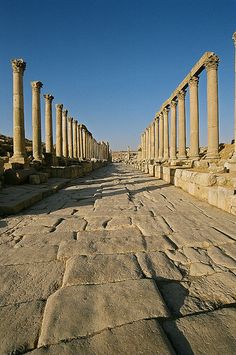 an empty street lined with columns and stone pavement