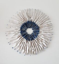 a white and blue object on a white surface with one circle made out of paper