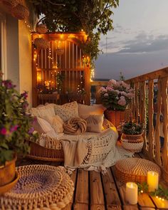 a balcony decorated with wicker furniture and flowers on the table, candles lite up in the background