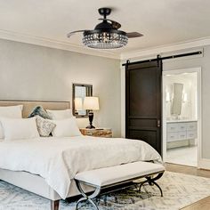 a bedroom with a bed, mirror and ceiling fan