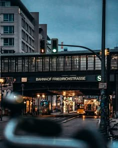 a bridge over a street with traffic lights and buildings in the background at night time