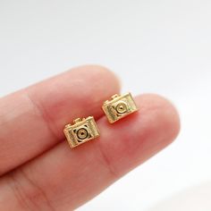 Beautiful and lovely tiny gold camera stud earrings. The post material is 925 silver post and the camera is 14K gold-plated brass. Your earrings will ship in a gift box. If you have any questions please feel free to contact me. Thanks :)    ♥ Earring size approx. 1/2" x 3/8" ♥Post Material 92.5 sterling silver post  ♥Real 14K Gold Plated ♥ 1 Pair ♥ Delivery Time Fast shipping within 1 - 3 days  ♥  See more Rudiana Accessories  Rudiana.etsy.com Camera Clay Earrings, Mini Camera Keychain, Camera Earrings, Gold Camera, Digital Camera Charm, Camera Charm, Camera Necklace, Photographer Gifts, Gold Engraving