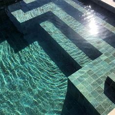 an empty swimming pool with clear blue water and sun reflecting off the tiles on it