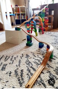 a child's play area with wooden toys on the floor and stairs in the background