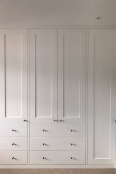 an empty room with white cupboards and carpeted flooring on the side wall