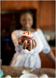 a woman holding a cupcake in her hand