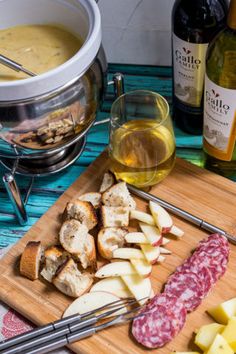 a cutting board with cheese, meat and wine on it