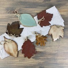 five leaf shaped cookies tied with twine on top of a wooden table next to each other