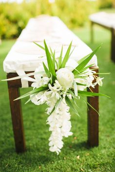 a bouquet of white flowers sitting on top of a wooden bench in the grass next to benches