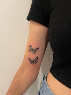 two butterflies tattoo on the right arm and left arm, with one butterfly flying in the air