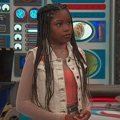 a woman with long braids standing in front of a tv set