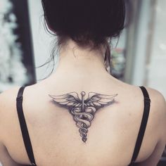 a woman's back with a medical symbol tattoo on her upper arm and shoulder