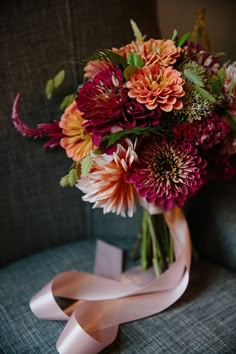 a bouquet of flowers sitting on top of a blue couch next to a pink ribbon